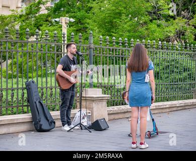 Bucharest, Romania - August 2022: Young street artist with a acoustic guitar playing in the center of Bucharest (Victory street - Calea Victoriei). Stock Photo