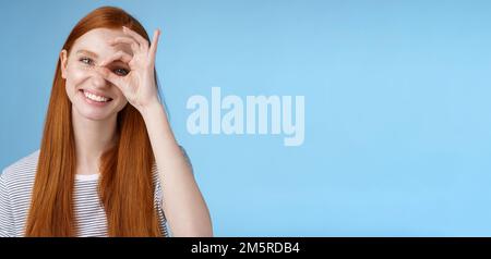 Charismatic happy adorable redhead teenage girl sincere eyes making circle eye show okay ok sign delighted like approve cool idea smiling satisfied Stock Photo