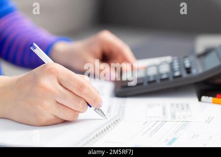 Woman using calculator for calculate domestic bills for paying taxes Stock Photo