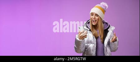 Bothered complaining dissatisfied cute blond girl yelling stupid smartphone standing unhappy recording audio message whining yelling mobile phone Stock Photo