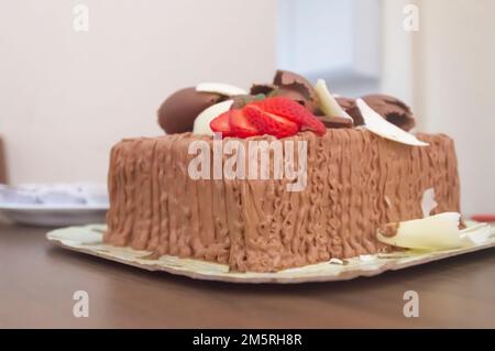 Birthday cake with candles in the shape of number 27 on a table mounted for a few people and a bottle of wine in the background,adult birthday concept Stock Photo