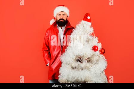 Winter holidays. Bearded businessman in Santa hat with Christmas tree. Happy New Year. Stock Photo