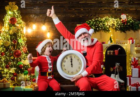 Santa Claus and little child boy with clock. Time to celebrate. New year midnight. Winter holidays. Stock Photo