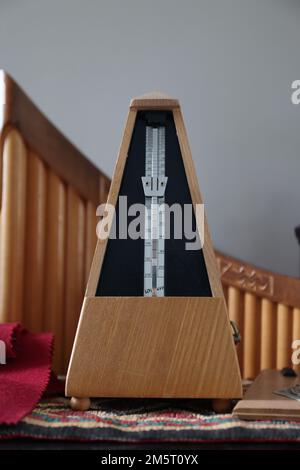 A vertical shot of a light brown Metronome on a table Stock Photo