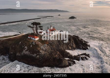 Drone view of waves crashing against rocks at Battery Point Lighthouse Stock Photo