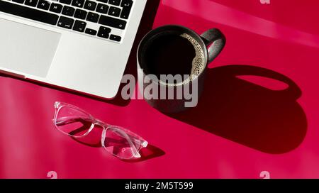 flat lay composition of notebook, coffee, computer and glasses on magenta background  Stock Photo