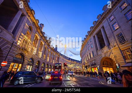 People and traffic along Regent Street in London, UK. Evening view of Regent Street with Christmas lights above the road Stock Photo