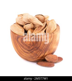 Mountain almonds in wooden bowl, isolated on white background. Uzbek wild almonds Stock Photo