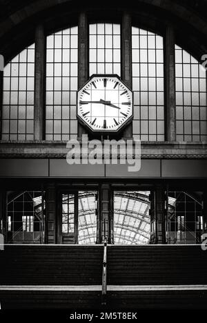 An old clock hanging from a wall in a railway station in Cologne, Germany Stock Photo