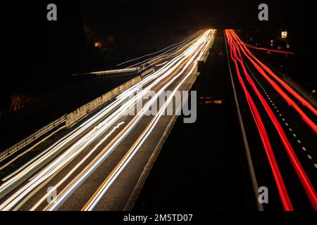 Cars light trails at night in curve asphalt road. Long exposure showing the movement of traffic from the bridge Stock Photo