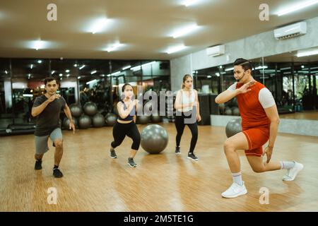 gymnastic instructor and group of sporty young people doing squats Stock Photo