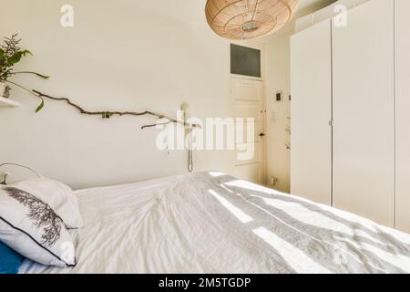 a bedroom with a bed and some plants on the headboards hanging from a ceiling light over the bed Stock Photo