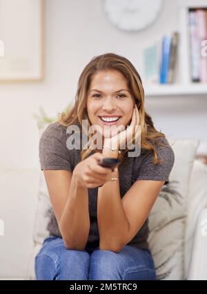 This looks like a good show to watch. a young woman spending a relaxing weekend at home watching tv. Stock Photo