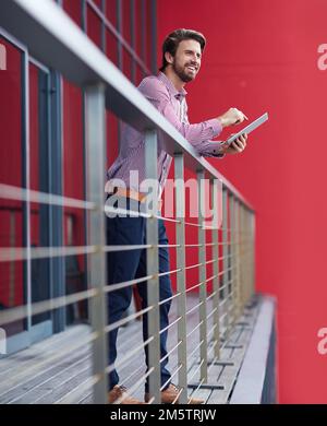 Using an entrepreneurial app to organize his day. a young businessman using a digital tablet on the balcony of an office building. Stock Photo