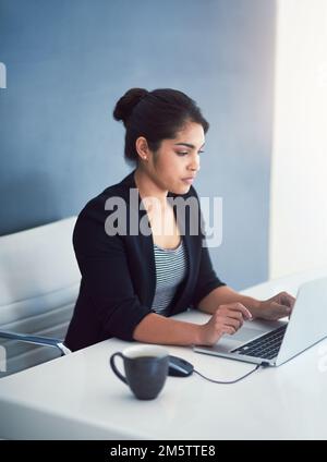 Showing her dedication. High angle shot of an attractive young businesswoman working on a laptop in her office. Stock Photo