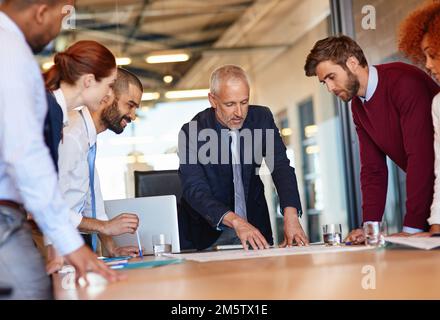Getting down to business. a group of businesspeople discussing documents in a meeting. Stock Photo