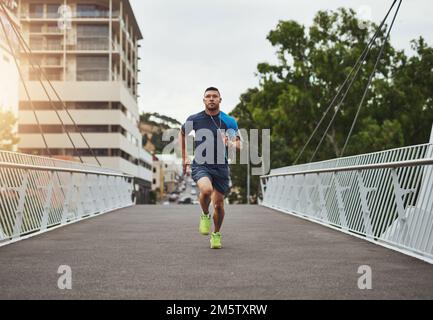 When your legs get tired, run with your heart. a young man out for a run in the city. Stock Photo