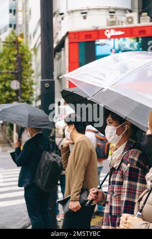 People walk scramble crossing with umbrella in Shibuya Ward, Tokyo on ...