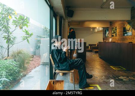 Young man sitting while using his phone in a boutique smoking room Stock Photo
