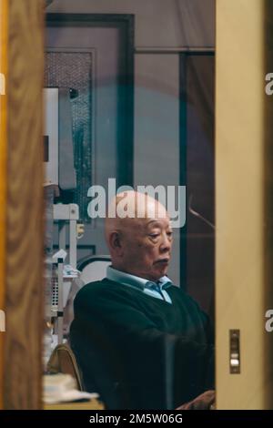 An elderly man sitting in an office Stock Photo