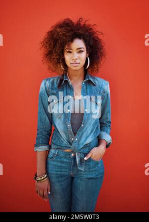 Beautiful and she knows it. Portrait of an attractive young woman posing against a red background. Stock Photo