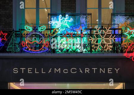 Stella McCartney brand logo and shop front with Christmas decorations and lights in Bond Street, London, UK Stock Photo