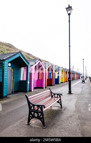 Colourful wooden beach huts at the North Yorkshire seaside town of Saltburn-by-the-Sea on a misty winter's day. Stock Photo