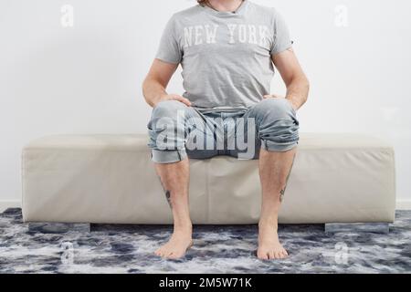 Man sitting barefoot on couch Stock Photo