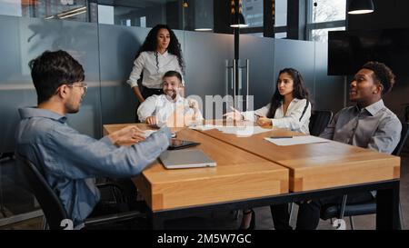 Multiracial business group in office meeting discuss project startup. Men and women coworkers partners team brainstorming ideas discussing marketing Stock Photo