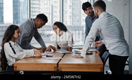 Multiracial business team coworkers partners people in office brainstorming paperwork negotiating discussing project at meeting multicultural Stock Photo