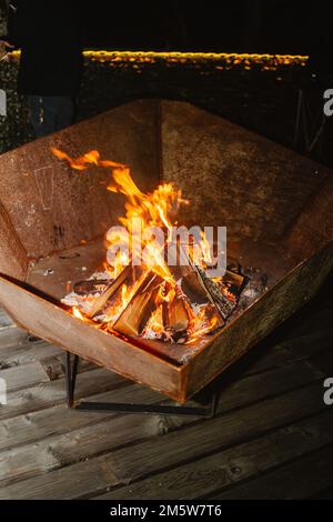 Bonfire Container A small fire is burning in a metal container. The container is ...