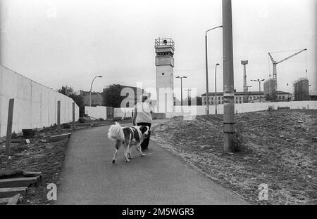 GDR, Berlin, 07. 06. 1990, Wall at the historic Bernauer Strasse (Nordbahnhof), woman with dog, watchtower, C Rolf Zoellner Stock Photo