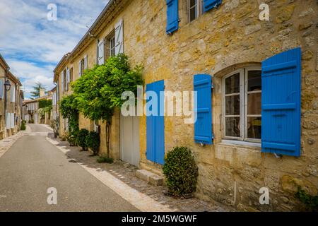 Quaint and flowery facades of townhouses with colorful wooden shutters and doors in the village of Terraube in the South of France (Gers) Stock Photo