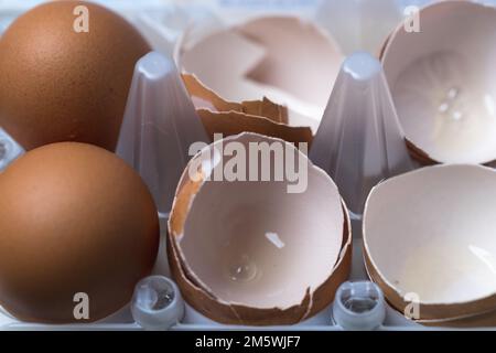 Pile of raw brown and white eggs with broken eggshells on straw. Baking ingredient detail. Stock Photo