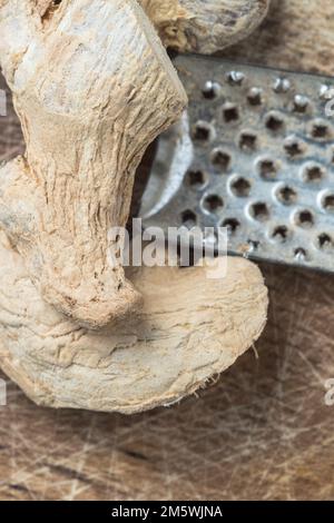 Healthy ingredient: Dried ginger on wood with a grater. Spice for cooking or tea. Stock Photo