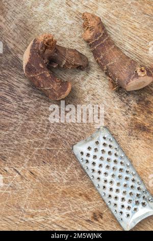 Rustic food prep: Dried ginger root pieces and grater on wood background. Stock Photo
