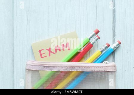 exam word in a sticky note and pencils on color background  Stock Photo