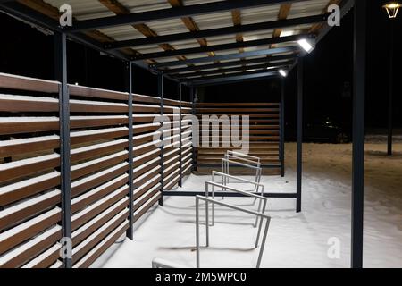 Empty shed with bicycle racks in a city park in winter. Difficulties in traveling by bike in winter. Stock Photo