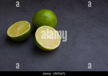 Fresh ripe limes on dark stone background. Top view with copy space Stock Photo