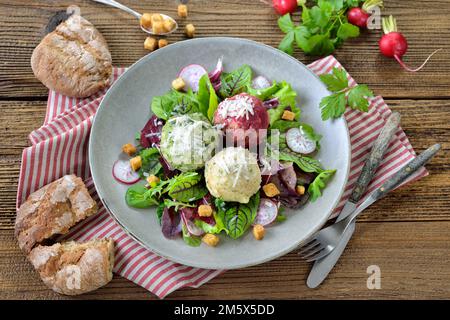 Homemade traditional South Tyrolean dumpling trio, consisting of the three different kinds spinach, cheese and beetroot, on leaf salad with croutons Stock Photo