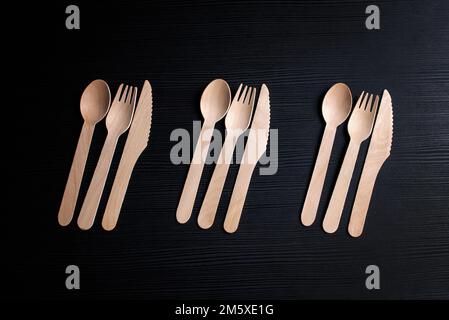 disposable eco-friendly wooden spoons, forks and knives on a dark background Stock Photo