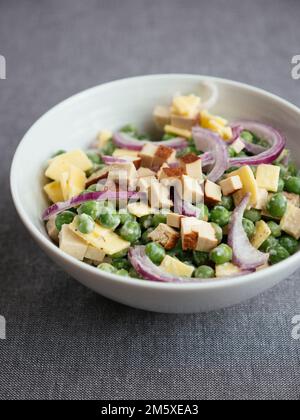 Vegan pea salad with non-dairy cheese and smokey tofu Stock Photo