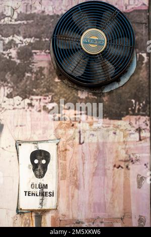 Risk of death sign. Skull sign, Death risk. Street fan by Güçtay. Greasy dirty wall in central Antalya Turkey Stock Photo