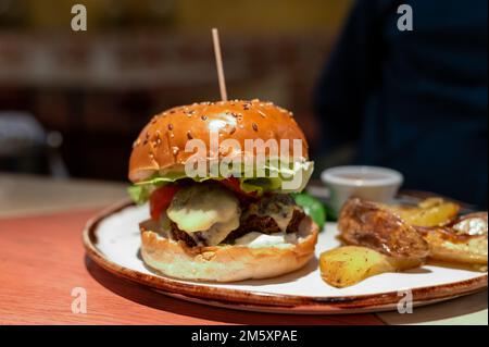 Healthy food, organic vegetarian burger with plant based falafel balls, vegan cheese, green lettuce and baked potatoes Stock Photo