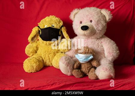 children's soft plush toys in medical mask lie on the red sofa, healthcare and medicine, children's morbidity Stock Photo