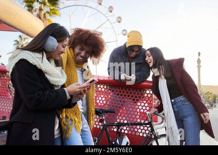 Group of young mixed race people in winter clothes with cell phones outdoors. Technology friends Stock Photo