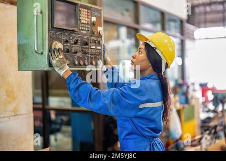 Mechanical woman in uniform working in machinery shop trouble shooting electrical controller box Stock Photo