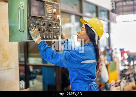 Mechanical woman in uniform working in machinery shop trouble shooting electrical controller box Stock Photo