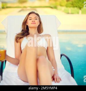 Summertime and the livin is easy. an attractive young woman enjoying a poolside drink. Stock Photo