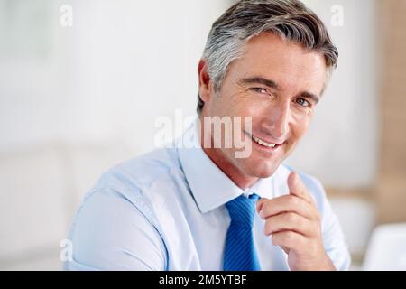 I went out and got my success. Portrait of a confident mature businessman wearing a suit and sitting indoors while pointing at the camera. Stock Photo